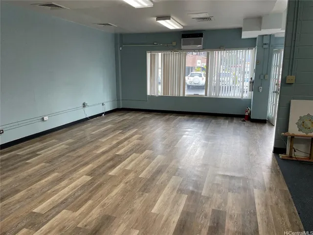 a view of an empty room with a window and wooden floor