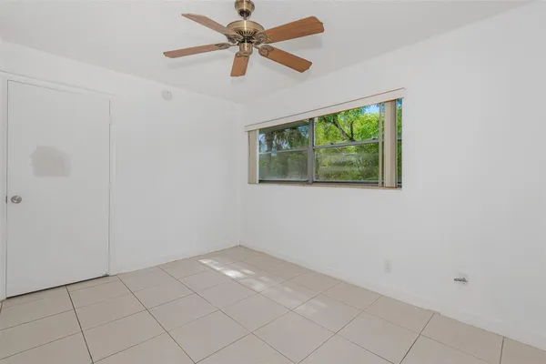 an empty room with a window and a fan
