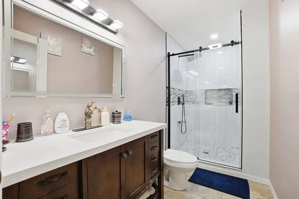 a bathroom with a granite countertop sink toilet a mirror a vanity and shower
