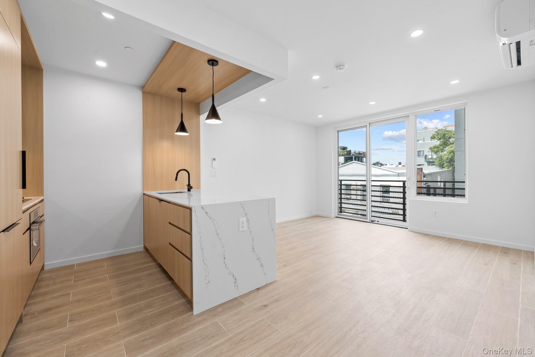 366 Harman Street, Unit 4F Brooklyn, NY 11237 - Photo 5 of 17 Kitchen featuring wood finish floors, recessed lighting, light stone countertops, a peninsula, and hanging light fixtures