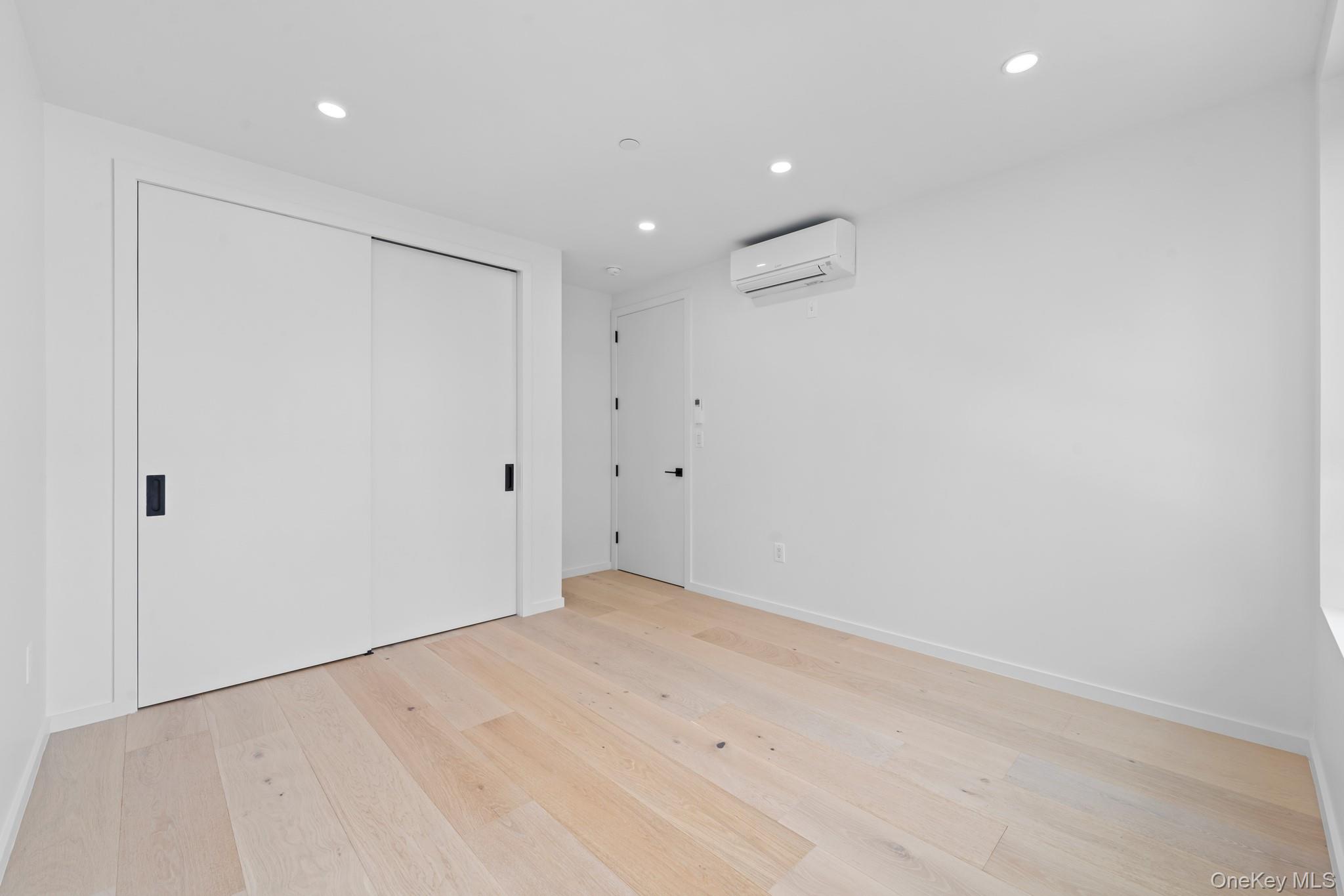366 Harman Street, Unit 4F Brooklyn, NY 11237 - Photo 10 of 17 Unfurnished bedroom with recessed lighting, light wood-type flooring, a closet, and a wall unit AC
