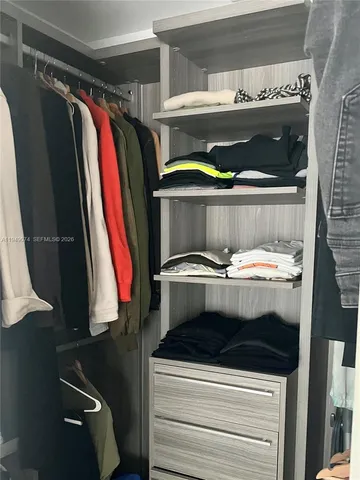 a view of walk in closet with clothes and shoes