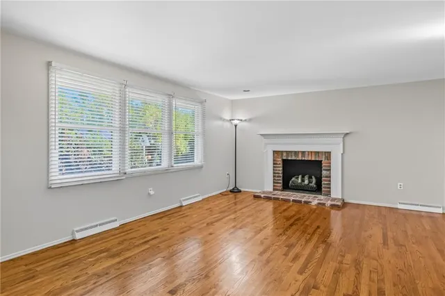 an empty room with wooden floor fireplace and windows