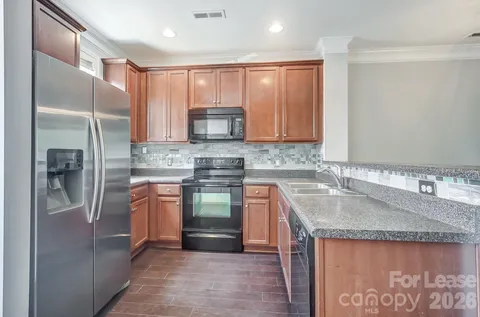 a kitchen with stainless steel appliances granite countertop a sink stove microwave and refrigerator