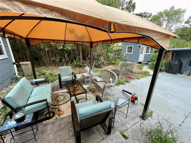 a view of a patio with couches table and chairs under an umbrella