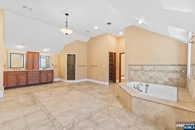 a bathroom with a tub a sink and a large mirror