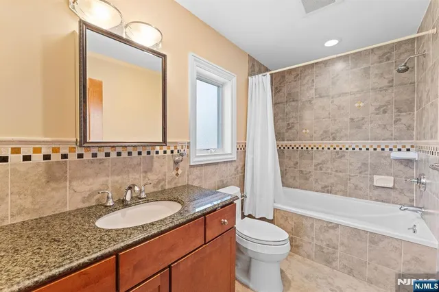 a bathroom with a granite countertop sink mirror vanity and toilet