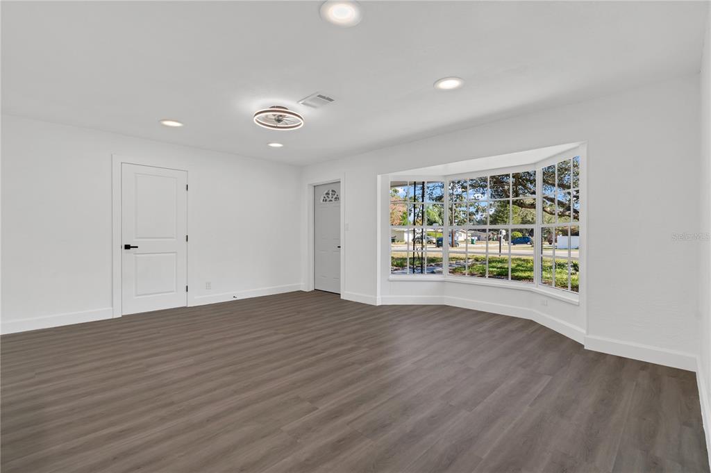 11598 Ridge Road Largo, FL 33778 - Photo 16 of 29 a view of an empty room with wooden floor and a window