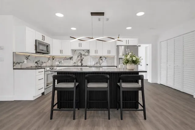a kitchen with a dining table chairs and wooden floor