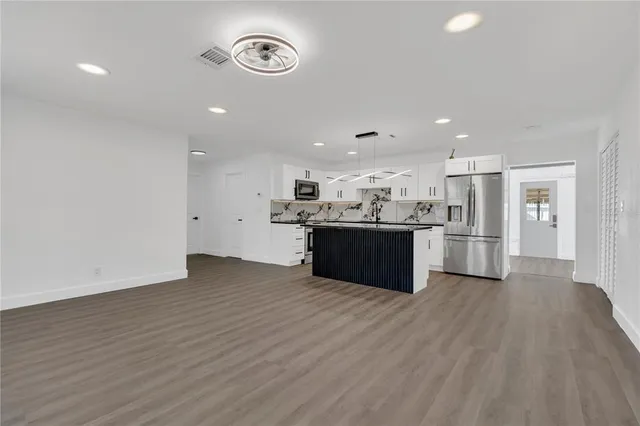 a large kitchen with stainless steel appliances granite countertop a large counter top and wooden floors