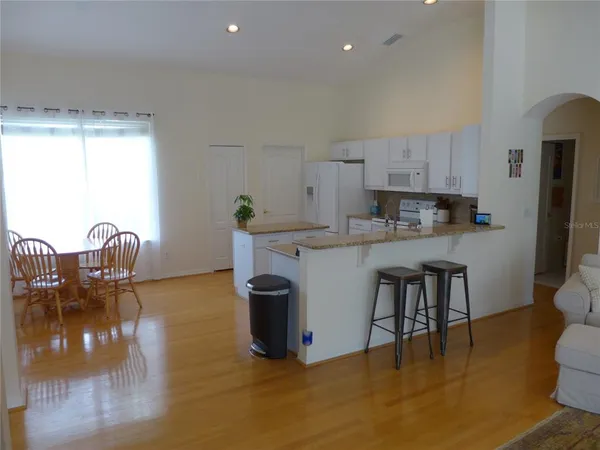 a kitchen with stainless steel appliances granite countertop a stove a sink a microwave a dining table and chairs with wooden floor