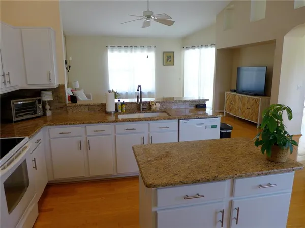 a kitchen with granite countertop a sink white cabinets and stainless steel appliances