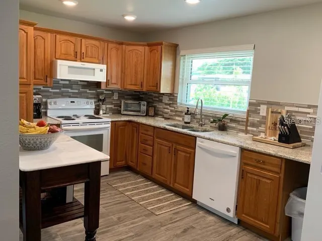 a kitchen with stainless steel appliances granite countertop wooden cabinets sink and a window