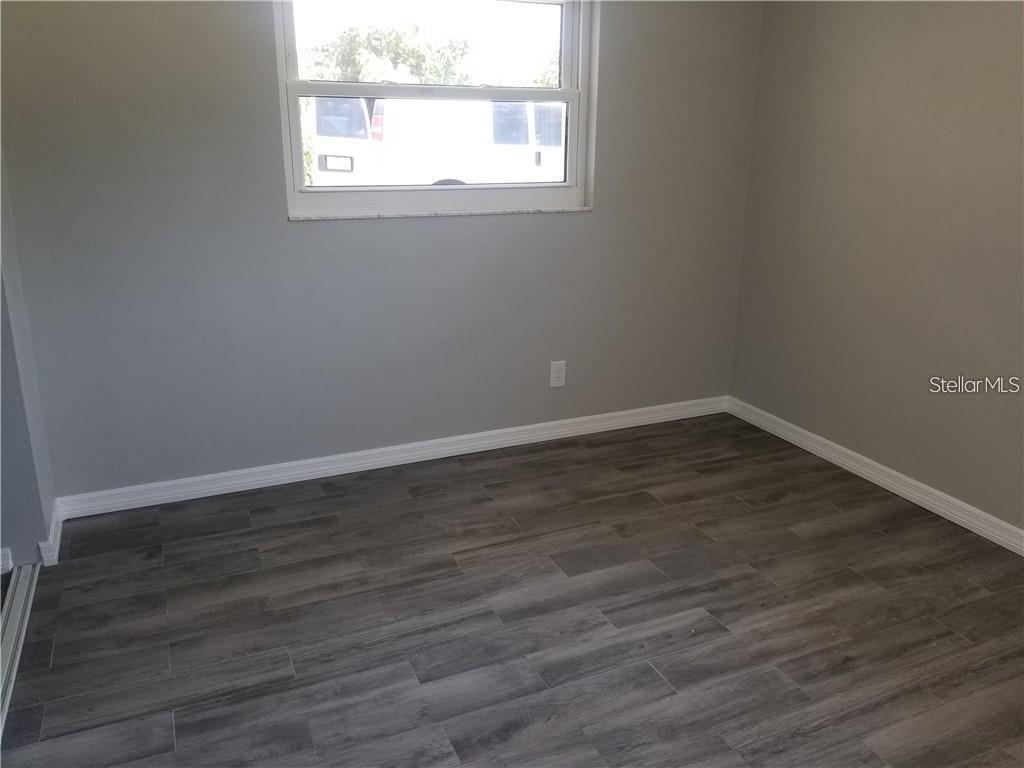 527 Eastview Road Largo, FL 33770 - Photo 9 of 14 an empty room with wooden floor and windows