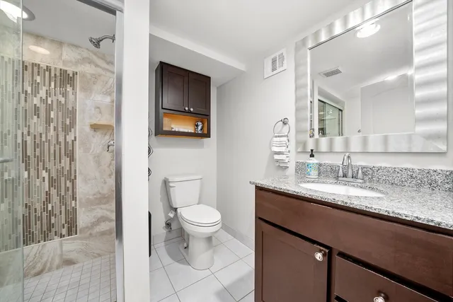 a bathroom with a granite countertop sink toilet and shower