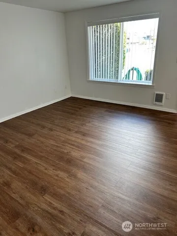 a view of an empty room with wooden floor and a window