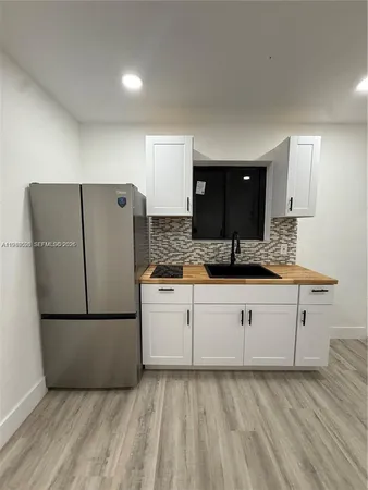 a kitchen with granite countertop a refrigerator sink and cabinets