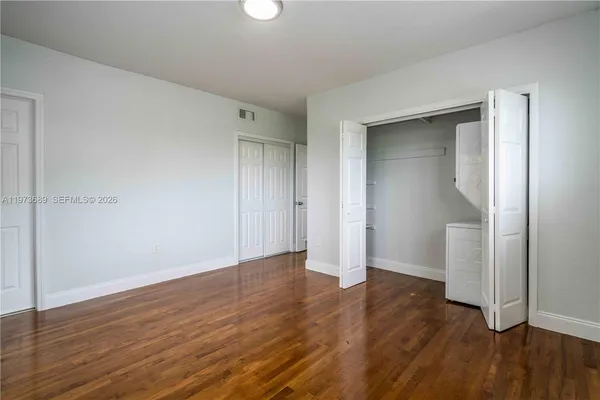 an empty room with wooden floor & closet area