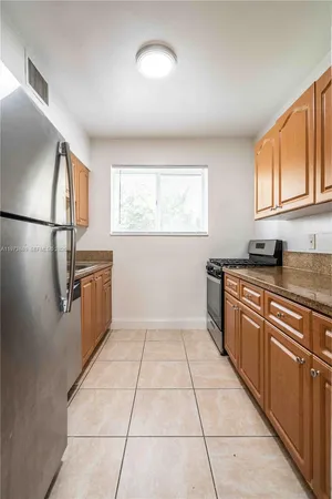 a kitchen with granite countertop a refrigerator and a stove top oven