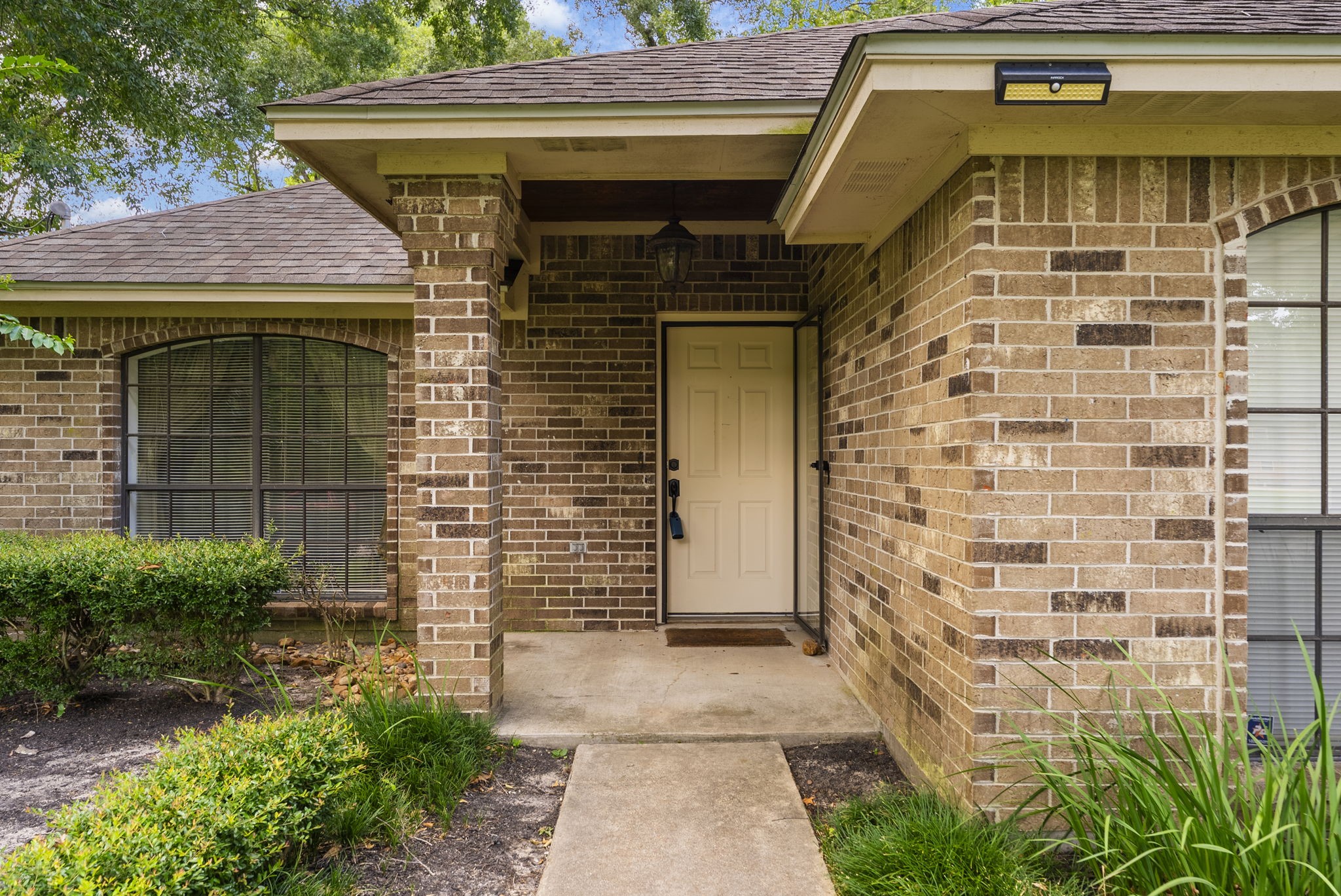 202 Sunset Boulevard Conroe, TX 77303 - Photo 6 of 50 This inviting front porch, framed by classic brickwork and lush greenery, offers a warm welcome and sets the stage for a cozy home experience.