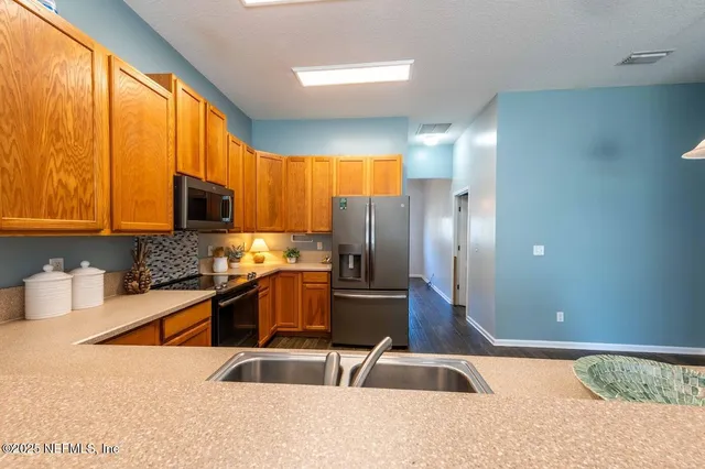 a kitchen with stainless steel appliances granite countertop a sink a stove and a refrigerator