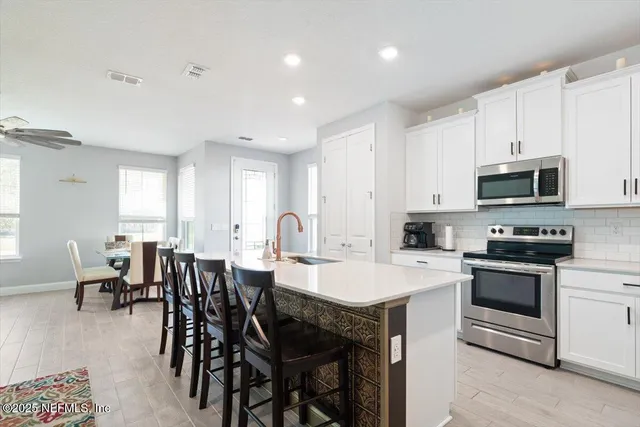 a kitchen with appliances a sink dining table and chairs