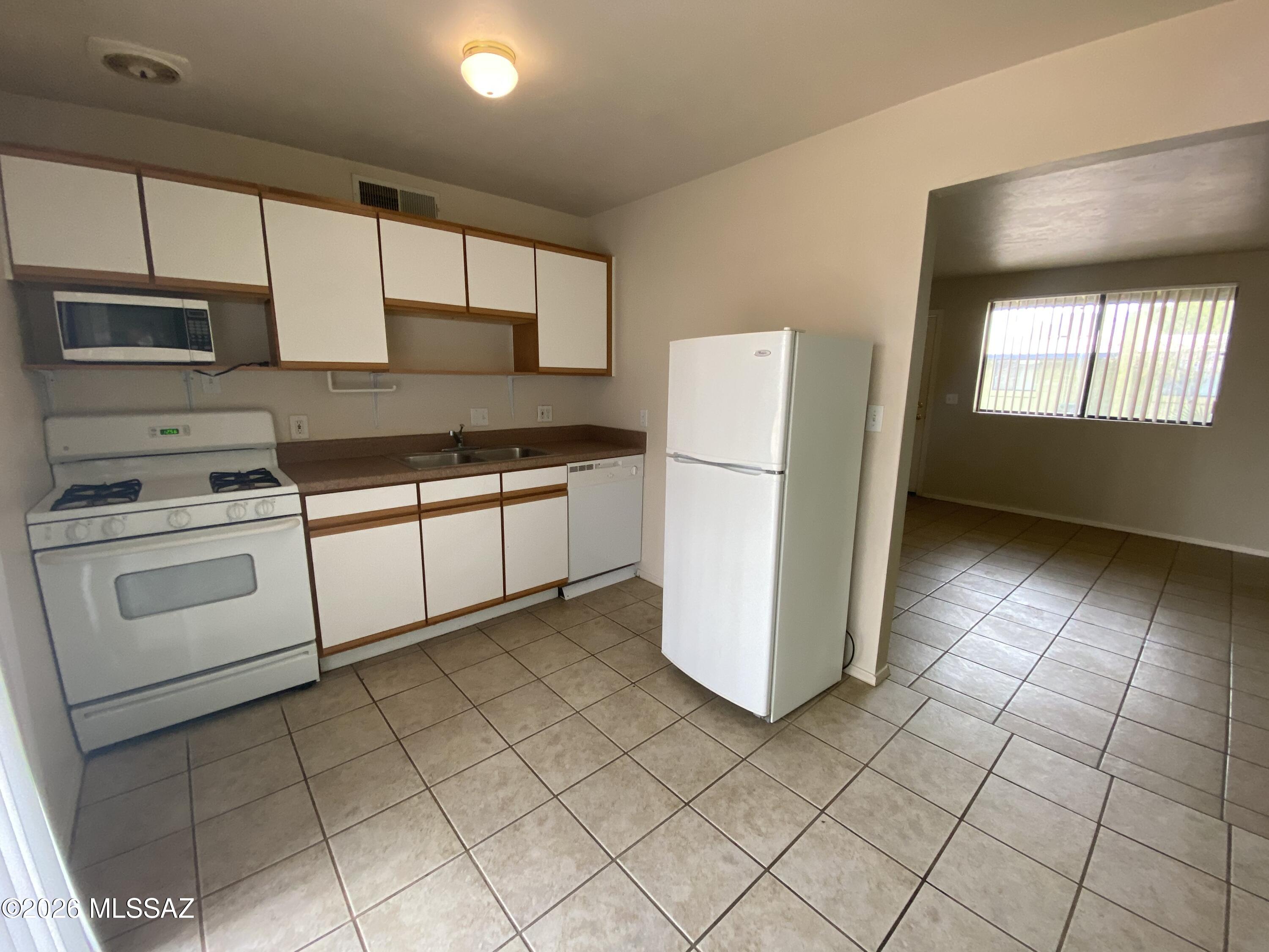 350 North Silverbell Road, Unit 94 Tucson, AZ 85745 - Photo 4 of 15 a kitchen with a stove a refrigerator and cabinets