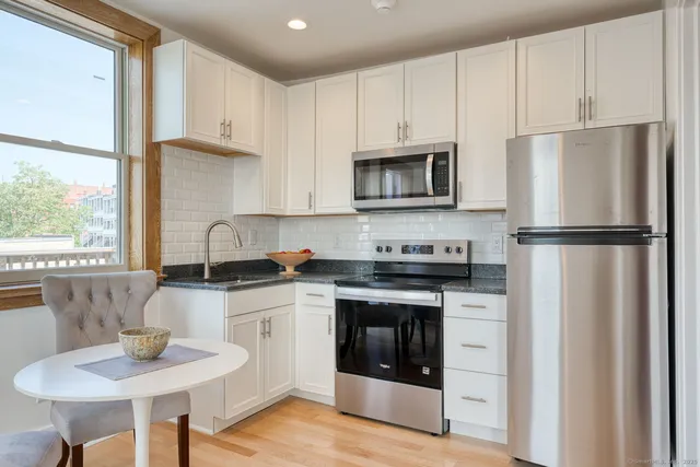 a kitchen with stainless steel appliances granite countertop a stove a refrigerator and a sink with wooden cabinets