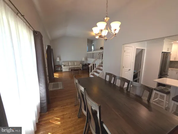 a kitchen with stainless steel appliances a refrigerator a sink a stove and white cabinets with wooden floor