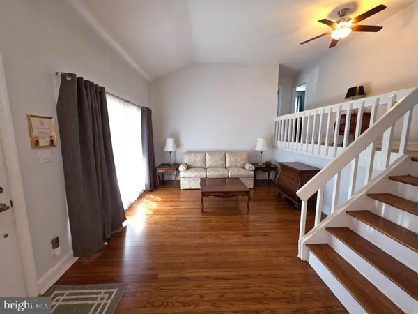 a living room with furniture stairs and a wooden floor