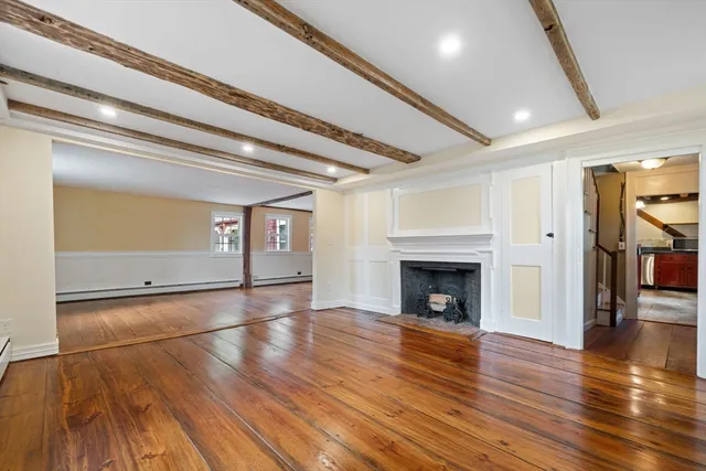 an empty room with wooden floor fireplace and windows