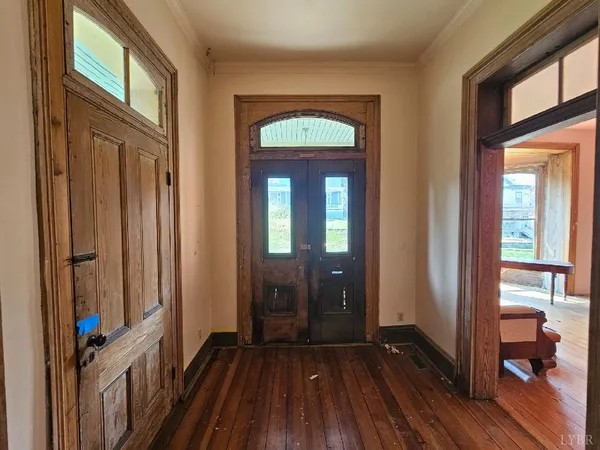 a view of a room with wooden floor front door and windows