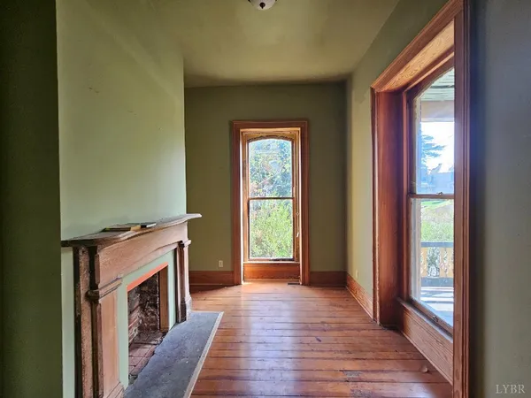 a hallway with wooden floor fireplace and windows