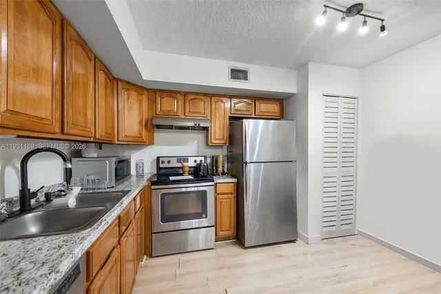 a kitchen with stainless steel appliances granite countertop a refrigerator sink and stove