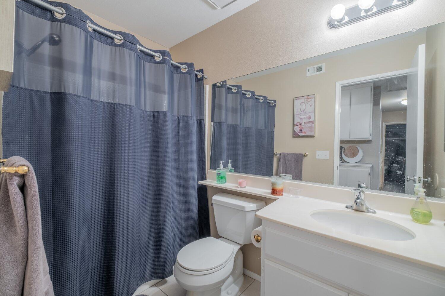 44628 Shadowcrest Drive Lancaster, CA 93536 - Photo 9 of 23 a bathroom with a sink a toilet a mirror and shower curtain