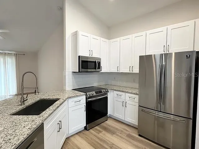 a kitchen with a sink white cabinets and stainless steel appliances