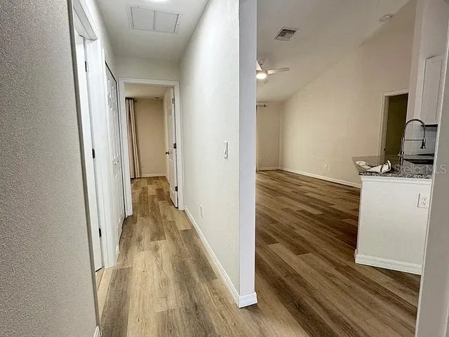 a view of a hallway with wooden floor and a bathroom