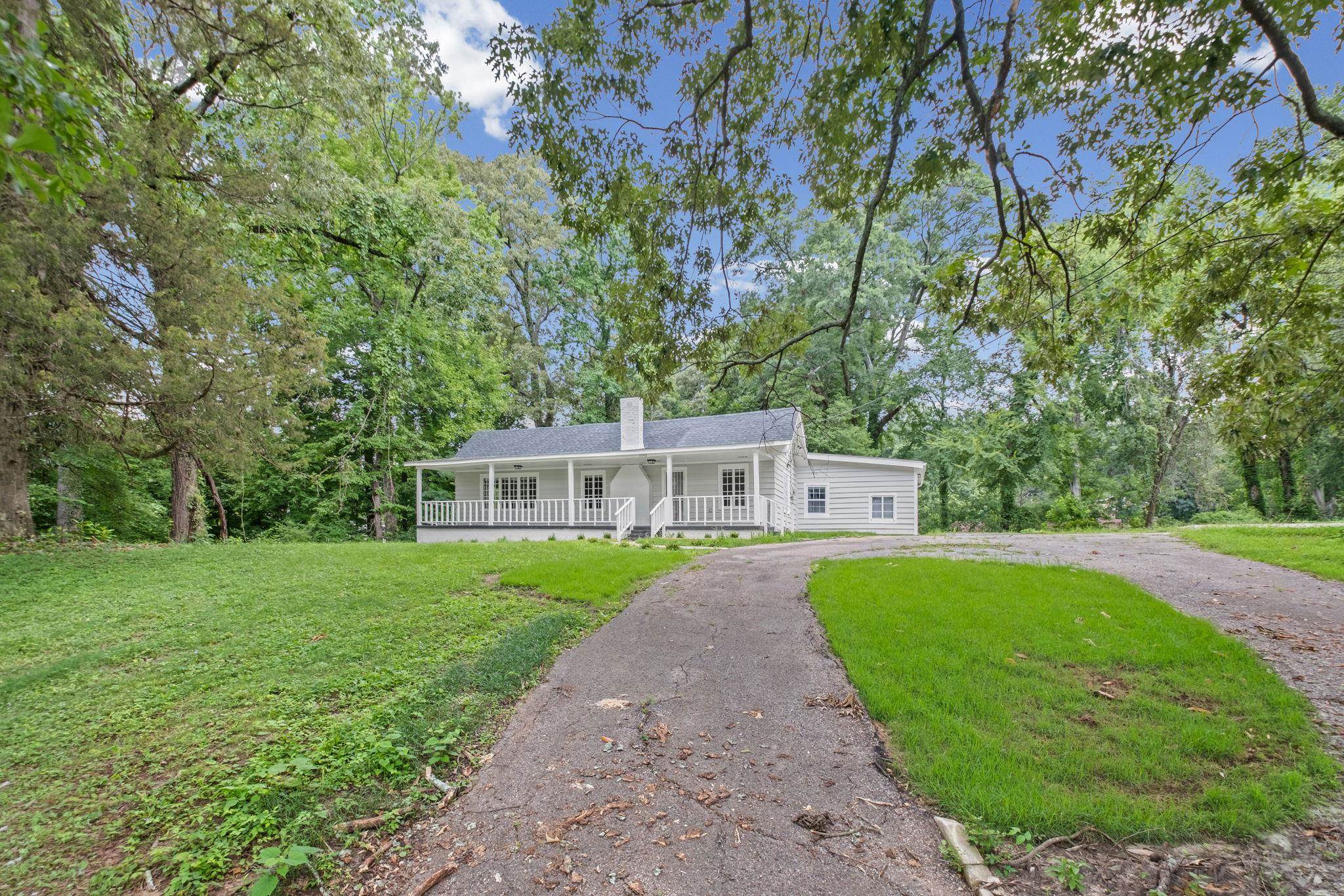 3942 James Road Memphis, TN 38128 - Photo 24 of 25 White exterior residence featuring a covered front porch with white railings, a prominent central chimney, and a dark gray roof