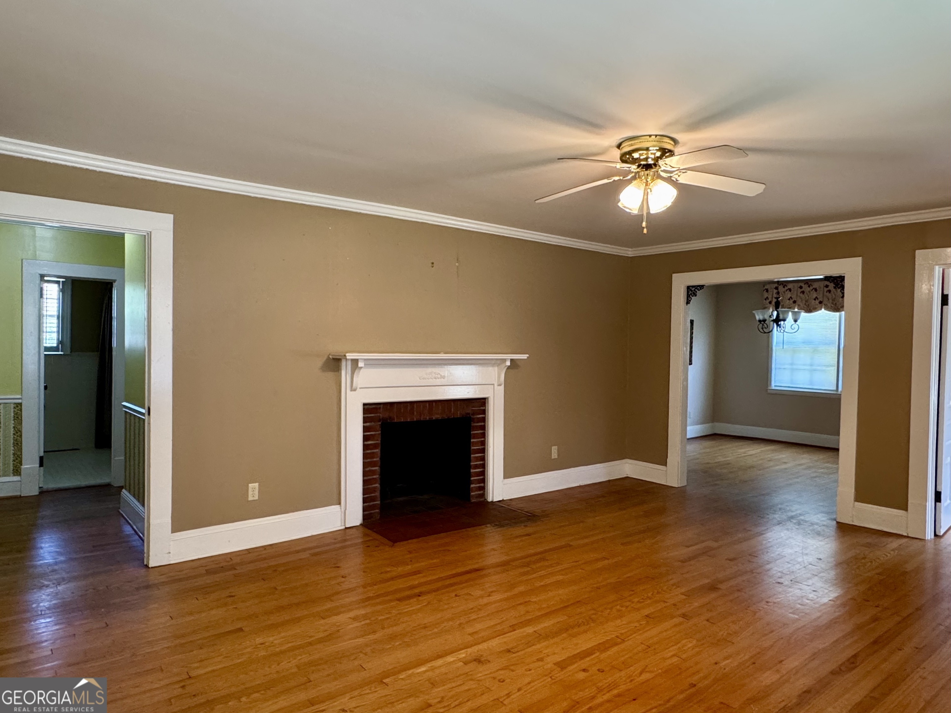 324 North Rhodes Street Union Point, GA 30669 - Photo 10 of 94 an empty room with wooden floor fireplace and windows