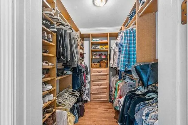 a view of walk in closet with clothes and shoes
