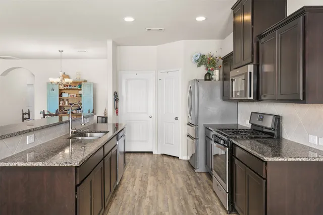 a kitchen with stainless steel appliances granite countertop a sink stove and refrigerator