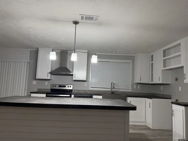 a kitchen with kitchen island granite countertop a sink a stove and a refrigerator