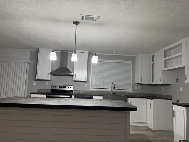 a kitchen with kitchen island granite countertop a sink a stove and a refrigerator