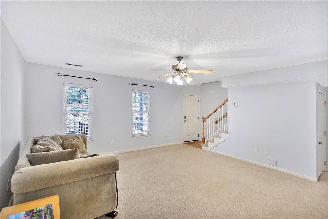 This inviting living area features a welcoming entry, plush carpeting, and abundant natural light.