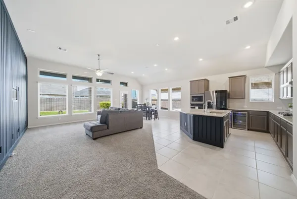 a large living room with stainless steel appliances kitchen island granite countertop a large window