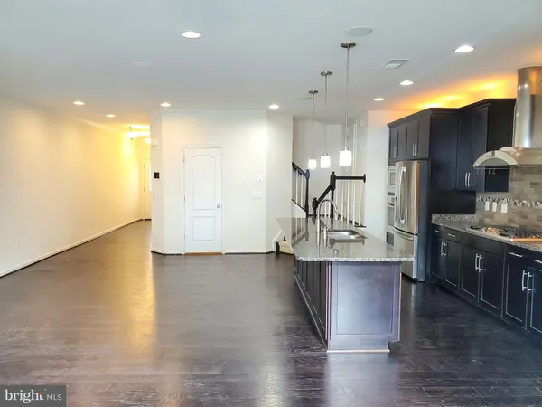 a large kitchen with stainless steel appliances kitchen island a large counter top and a wooden floors