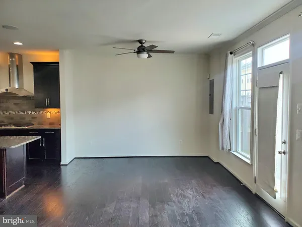 an empty room with wooden floor cabinet and windows
