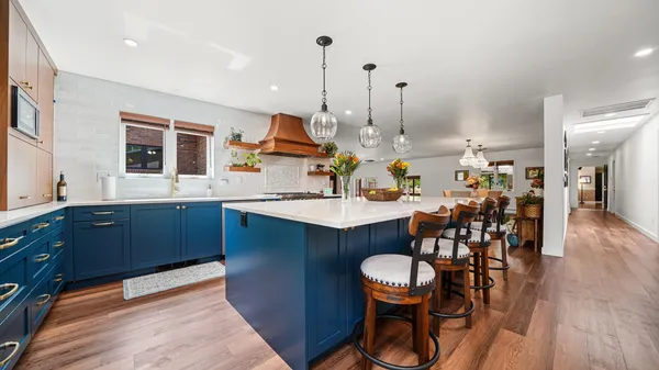 a kitchen with large wooden cabinets appliances and dining table