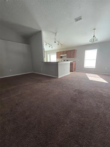 a view of a kitchen and empty room with windows