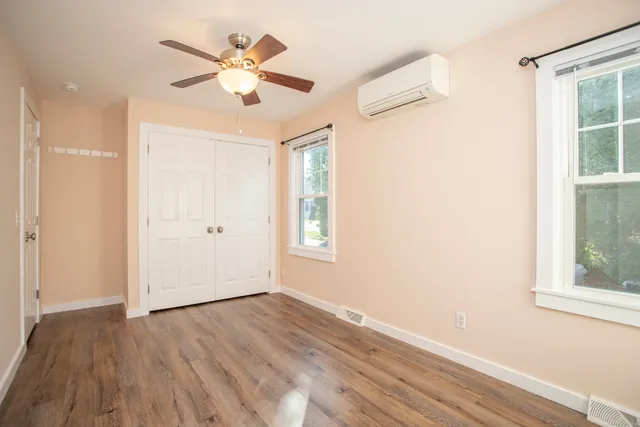 an empty room with wooden floor chandelier fan and windows